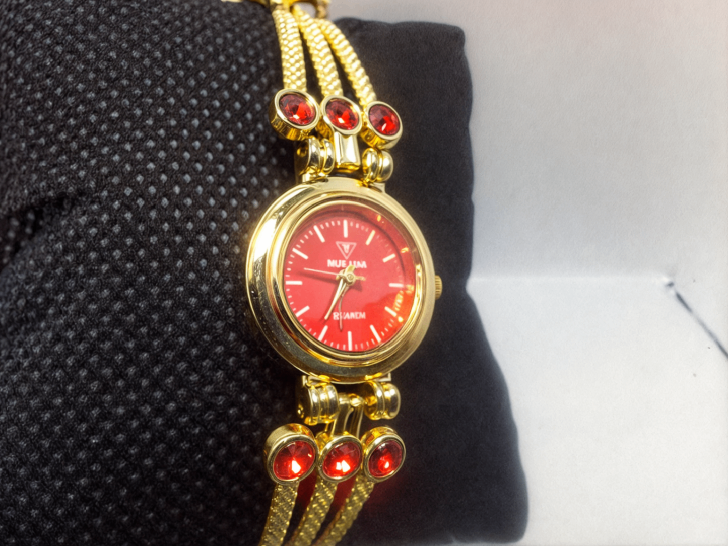 red faced gold bracelet watch on black pillow