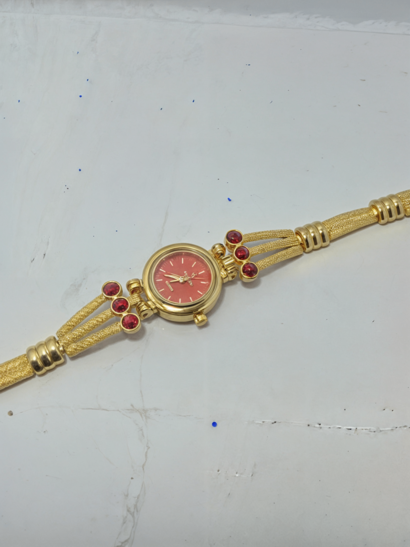 golden bracelet watch on white surface 