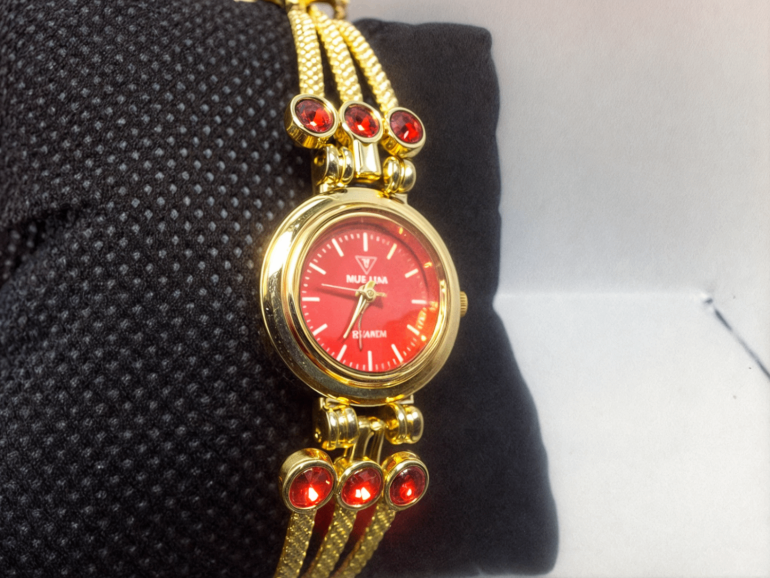 red faced gold bracelet watch on black pillow 