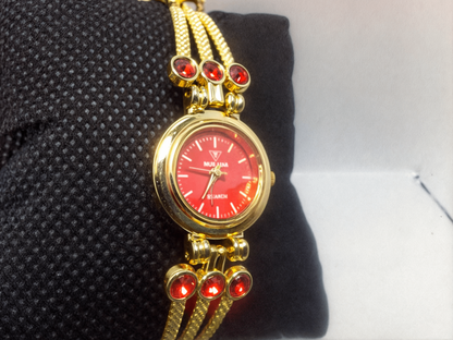 red faced gold bracelet watch on black pillow 