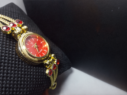 gold bracelet watch with red face with black background